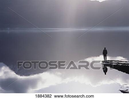 Stock Image - Woman Standing On The End Of A Pier Beside Loch Torridon. Fotosearch