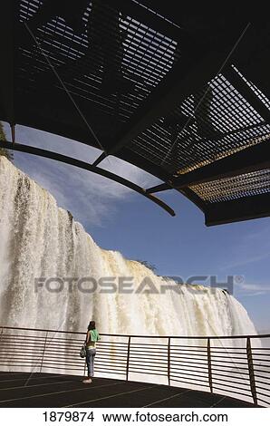 Picture - Woman Standing On Viewing Platform Looking At Iguacu Falls. Fotosearch