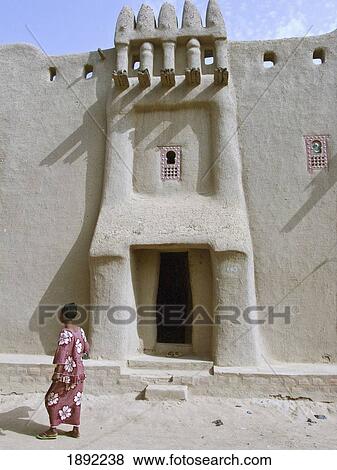 Stock Photo - Woman Standing Outside Tukulor House. Fotosearch
