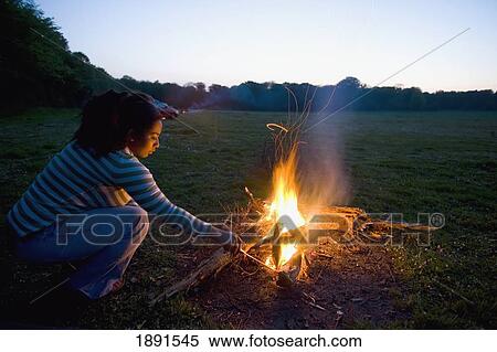 Stock Photography - Woman Stoking Camp Fire. Fotosearch