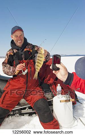 Woman taking a cell phone picture of an ice fisherman holding a winter walleye catch; Ontario, Canada View Large Photo Image Stock Image - Woman taking a cell phone picture of an ice fisherman holding a winter walleye catch; Ontario, Canada. Fotosearch
