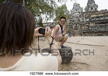 Stock Photograph - Woman Taking Photo Man At Temples Of Angkor, Siem Reap, Cambodia. Fotosearch