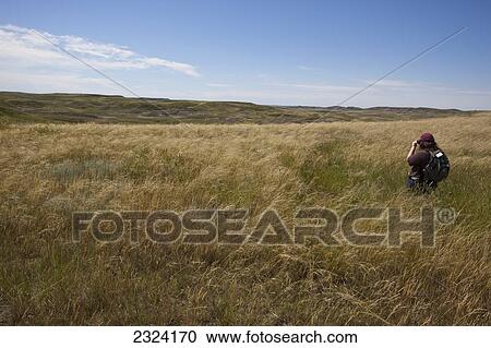 Stock Image - Woman taking photos in the East Block of Grasslands National Park; Saskatchewan, Canada. Fotosearch