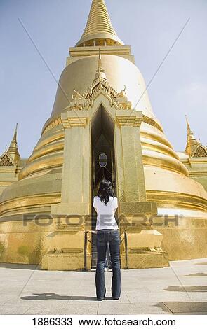 Stock Image - Woman Taking Pictures Of Phra Si Ratana Chedi At The Grand Palace. Fotosearch