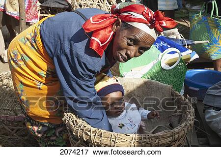 Woman Tending To A Baby In A Basket At The Weekly Market In Fianarantsoa, Madagascar View Large Photo Image Stock Photo - Woman Tending To A Baby In A Basket At The Weekly Market In Fianarantsoa, Madagascar. Fotosearch