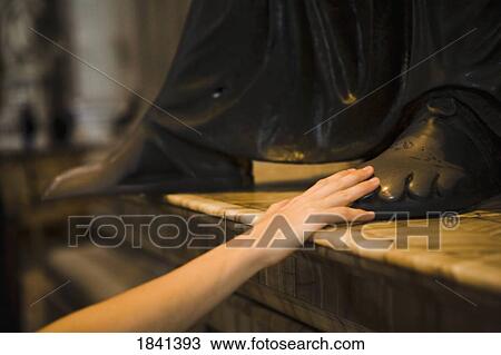 Stock Image - Woman Touching Foot Of Sculpture In Saint Peter's Basilica; Vatican City, Rome, Italy. Fotosearch