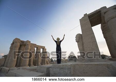Picture - Woman Tourist With Arms Raised At The Ramesseum, Luxor, Nile Valley, Egypt. Fotosearch
