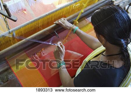 Stock Image - Woman Using Loom Weaving Fabric In Factory. Fotosearch