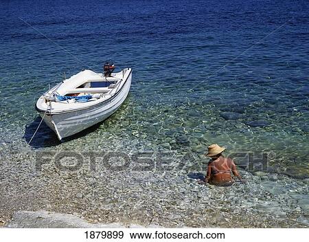 Stock Photo - Woman Wading In Water Next To Boat, Corfu. Fotosearch
