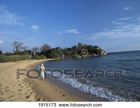 Stock Image - Woman Walking Along Beach. Fotosearch