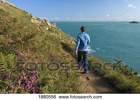 Stock Photograph - Woman Walking Along Coastal Path At The Pointe Du Grouin. Fotosearch