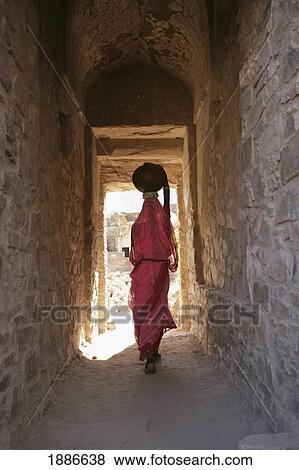 Woman Walking Between Two Stock Buildings Carrying A Pot On Her Head View Large Photo Image Stock Photo - Woman Walking Between Two Stock Buildings Carrying A Pot On Her Head. Fotosearch