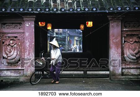 Stock Image - Woman Walking By Bicycle Out Of Roof Covered Bridge. Fotosearch