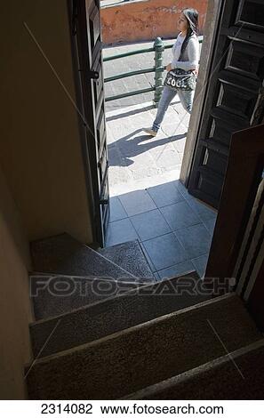 Stock Image - Woman walking by open door to staircase; Guanajuato, Guanajuato, Mexico. Fotosearch