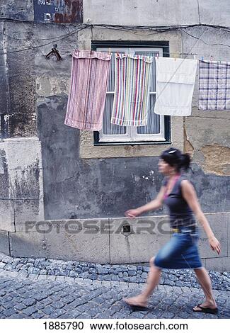 Stock Image - Woman Walking By Washing Line, Alfama. Fotosearch