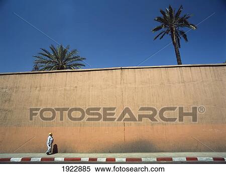 Stock Photography - Woman Walking On Street Next To Wall. Fotosearch