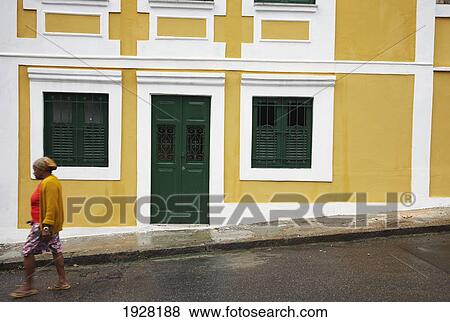 Stock Photo - Woman Walking Past Coloured Houses. Fotosearch