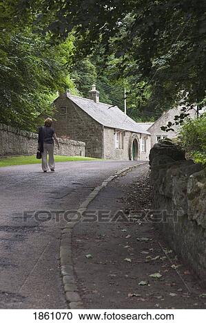 Stock Image - Woman Walking Up Country Road, Ford And Etal, Northumberland, England. Fotosearch