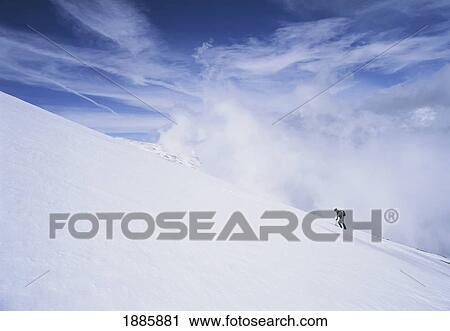 Stock Image - Woman Walking Up Snowy Slope In The Sierra Nevada Mountains. Fotosearch