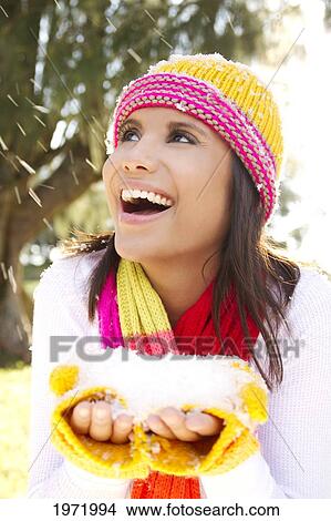 Picture - Woman Wearing Winter Clothing In Snowy Environment, Holding Snow In Hands.. Fotosearch