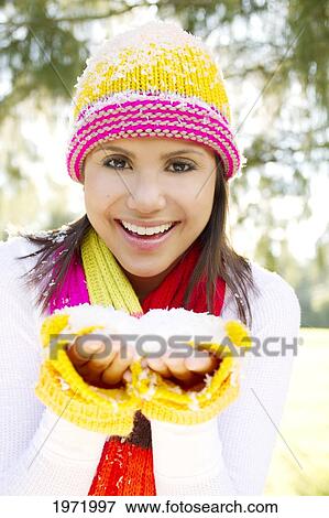 Stock Photo - Woman Wearing Winter Clothing In Snowy Environment, Holding Snow In Hands.. Fotosearch