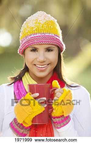 Stock Photo - Woman Wearing Winter Clothing In Snowy Environment, Holding Hot Drink In Mug, Selective Focus On Mug.. Fotosearch