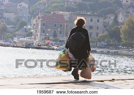 Woman With Bags Along The Waterfront, Split, Split-Dalmatia, Croatia View Large Photo Image Stock Photo - Woman With Bags Along The Waterfront, Split, Split-Dalmatia, Croatia. Fotosearch