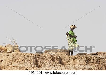 Stock Image - Woman with child along the shores of the Niger River between Mopti and Lake Debo, Mali. Fotosearch