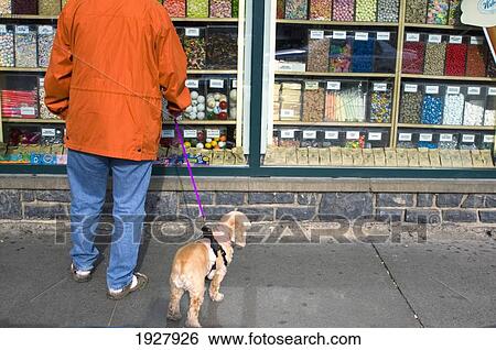 Stock Photograph - Woman With Dog On Leash Looking In Window Of Candy Shop, Low Sectio, Banff National Park, Alberta, Canada. Fotosearch