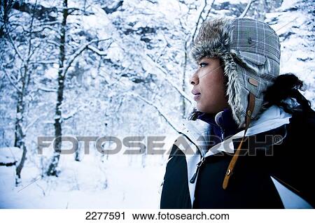 Stock Image - Woman with fur trimmed hat in the mountain woods, covered with snow in winter; Ortnevik, Sognefjord, Norway. Fotosearch