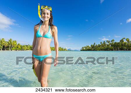 Stock Image - Woman with snorkel gear in aqua blue water; Tahaa, French Polynesia. Fotosearch