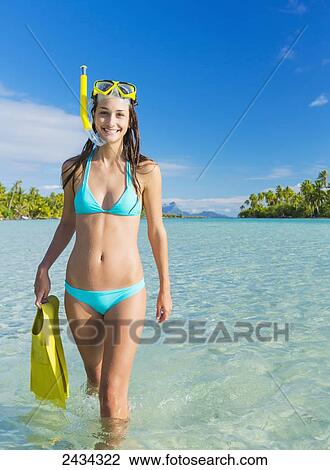 Stock Image - Woman with snorkel gear in aqua blue water; Tahaa, French Polynesia. Fotosearch