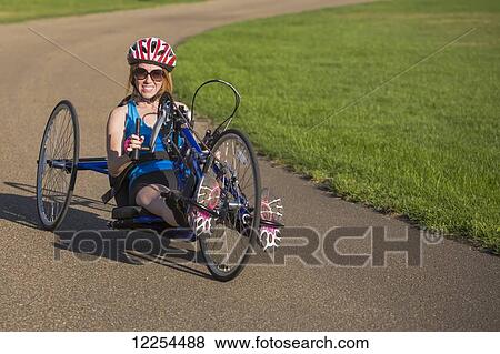Stock Photo - Woman with spinal cord injury cycling using hand propelled bicycle; Edmonton, Alberta, Canada. Fotosearch