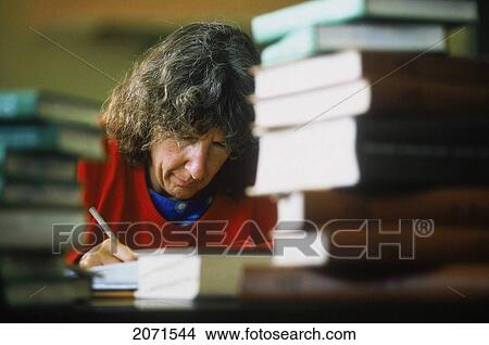 Picture - Woman Writing With Stacks Of Books. Fotosearch