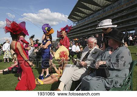 Stock Photography - Women and men in hats and fashionable clothes at new Grandstand Enclosure during Royal Ascot horse racing meeting., Berkshire, England.. Fotosearch
