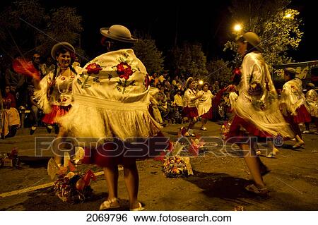 Stock Photograph - Women Dancing Around Festive Baskets In The Gran Entrada De Comadres Parade During The Carnaval Chapaco At Night, Tarija, Bolivia. Fotosearch