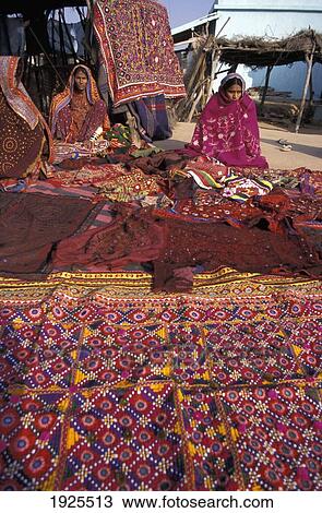Stock Image - Women Dressed In Colourful Saris Selling Red / Pink Textiles / Fabric / Material. Ludia Village, Marijan Tribe, North Of Bhuj. Fotosearch