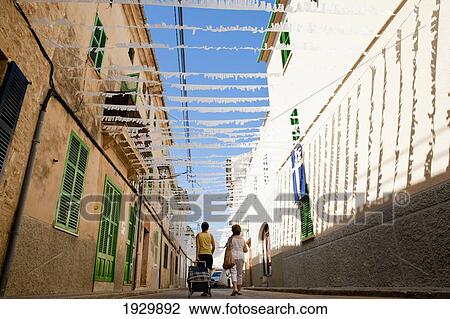 Stock Image - Women Going Shopping On A Decorated Street In Alcudia, Mallorca, Balearic Islands, Spain. Fotosearch
