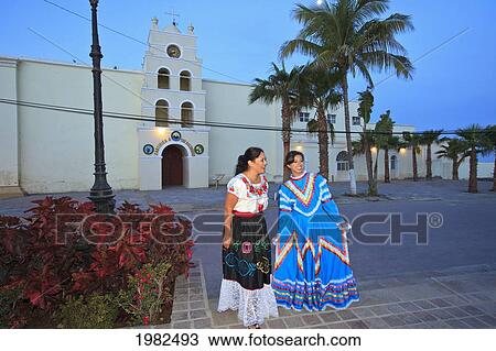 Stock Image - Women In Traditional Folkloric Dresses Downtown In The Early Morning; Todos Santos Baja California Sur Mexico. Fotosearch