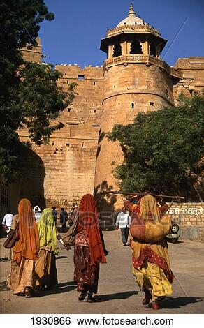 Women In Traditional Skirts And Scarves Walking Towards The Fort Gate At Jaisalmer, Rajasthan, India (C) Sue Carpenter/Axiom View Large Photo Image Stock Photograph - Women In Traditional Skirts And Scarves Walking Towards The Fort Gate At Jaisalmer, Rajasthan, India (C) Sue Carpenter/Axiom. Fotosearch