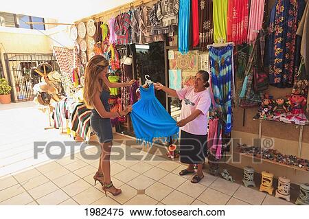 Stock Photography - Women Looking At A Dress At A Downtown Shop; Todos Santos Baja California Sur Mexico. Fotosearch
