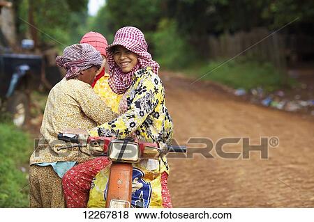 Stock Photo - Women on a motorbike; Mondulkiri, Cambodia. Fotosearch