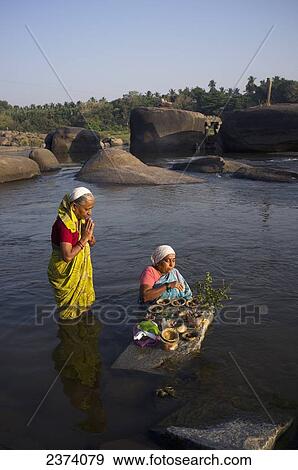 Stock Photo - Women standing in the river for a religious ceremony; Hampi, Karnataka, India. Fotosearch
