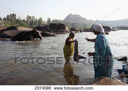 Women washing clothes in the river; Hampi, Karnataka, India View Large Photo Image Stock Image - Women washing clothes in the river; Hampi, Karnataka, India. Fotosearch