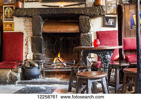 Wood burning fireplace with fire, old wooden stools, and metal legged wooden table; Athlone, County Westmeath, Ireland View Large Photo Image Stock Image - Wood burning fireplace with fire, old wooden stools, and metal legged wooden table; Athlone, County Westmeath, Ireland. Fotosearch