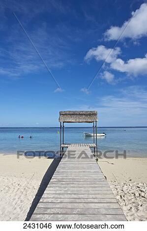 Stock Photograph - Wooden boardwalk over the white sand leading to the ocean; Mauritius. Fotosearch