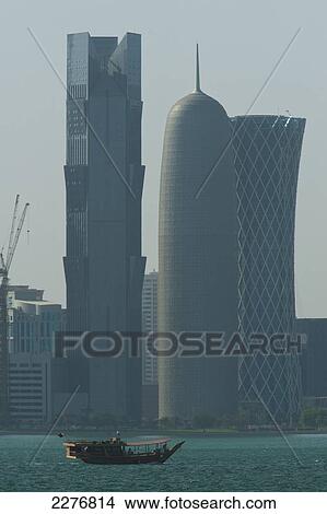 Picture - Wooden boat crossing harbour in front of the modern skyline of Doha; Doha, Qatar. Fotosearch