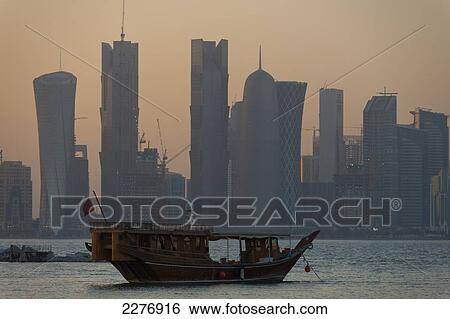 Wooden boat in the harbour at dusk with the modern city skyline behind; Doha, Qatar View Large Photo Image Stock Photograph - Wooden boat in the harbour at dusk with the modern city skyline behind; Doha, Qatar. Fotosearch