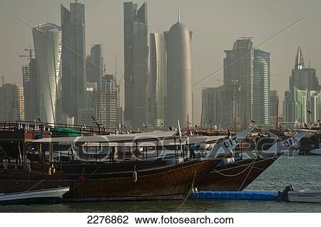 Stock Image - Wooden boats in the harbour with the modern skyline of Doha behind; Doha, Qatar. Fotosearch