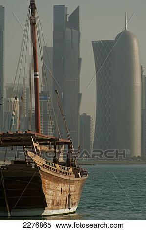 Stock Photography - Wooden boats in the harbour with the modern skyline of Doha behind; Doha, Qatar. Fotosearch